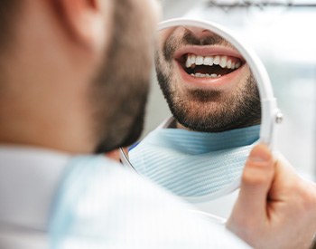 Patient smiling at reflection in handheld mirror
