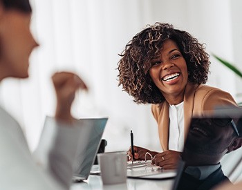 Woman smiling while taking notes during meeting