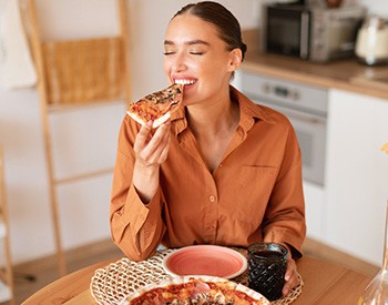 Woman enjoying slice of pizza at home