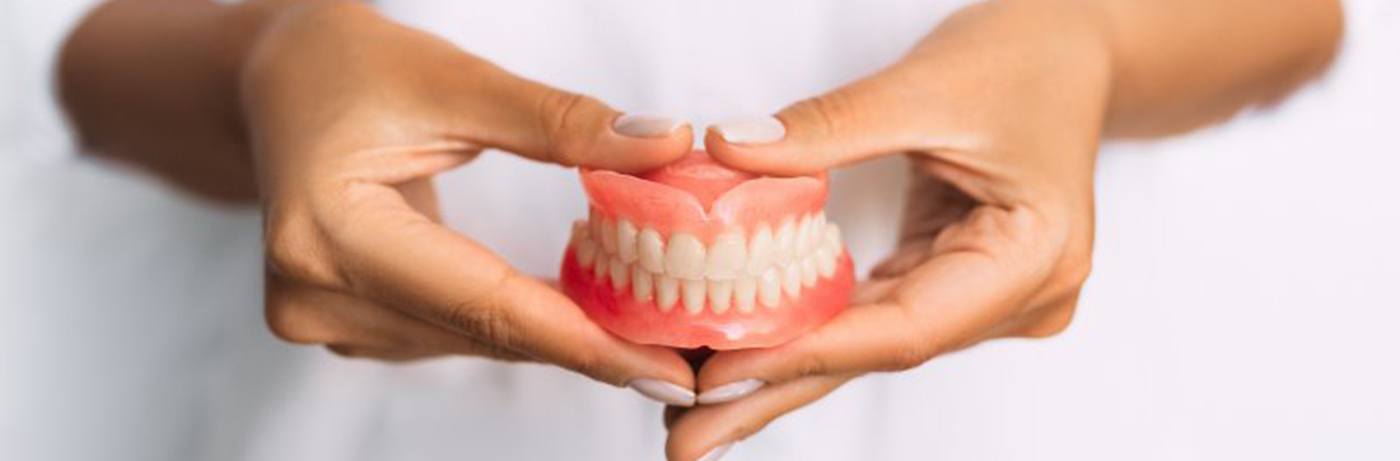 Close up of dentist holding a pair of dentures