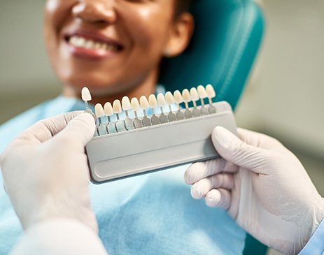 Dentist helping smiling patient select shade of veneer