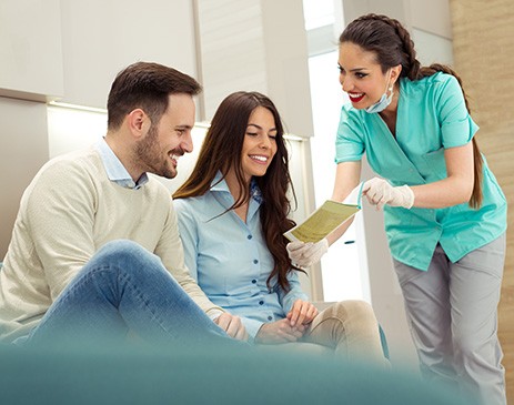 Dental assistant showing smiling couple form