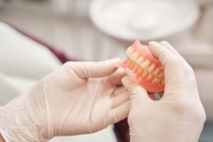 Gloved hands holding dentures. 