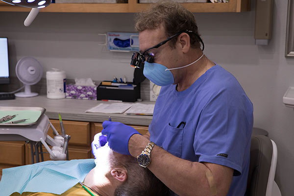 Dr. Harper performing a dental examination on a client laying back in a dental chair